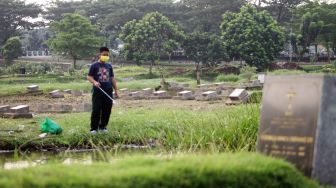 Warga memancing di TPU Tanah Kusir, Jakarta Selatan, Jumat (16/4/2021).  [Suara.com/Dian Latifah]
