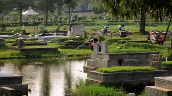 Warga memancing di TPU Tanah Kusir, Jakarta Selatan, Jumat (16/4/2021).  [Suara.com/Dian Latifah]
