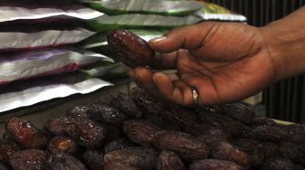 Pedagang menunjukkan buah kurma di kawasan Tanah Abang, Jakarta Pusat, Minggu (18/4/2021). [Suara.com/Dian Latifah]