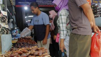 Pedagang melayani pembeli buah kurma di kawasan Tanah Abang, Jakarta Pusat, Minggu (18/4/2021). [Suara.com/Dian Latifah]