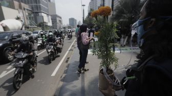 Aktivis lingkungan hidup membawa instalasi tanaman sebagai penyuplai oksigen saat menggelar aksi "Joget Jagat" di Jalan MH Thamrin, Jakarta, Kamis (22/4/2021). [Suara.com/Angga Budhiyanto]