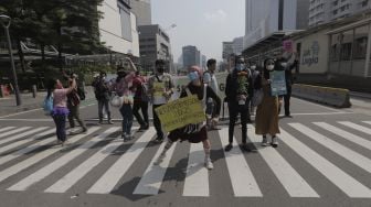 Aktivis lingkungan hidup menari saat menggelar aksi "Joget Jagat" di Jalan MH Thamrin, Jakarta, Kamis (22/4/2021). [Suara.com/Angga Budhiyanto]