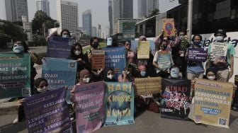 Aktivis lingkungan hidup membentangkan poster saat menggelar aksi "Joget Jagat" di Jalan MH Thamrin, Jakarta, Kamis (22/4/2021). [Suara.com/Angga Budhiyanto]