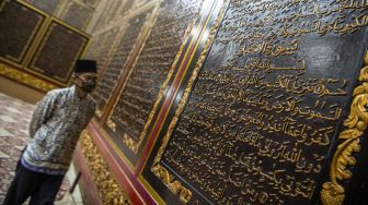 Pengunjung membaca ayat-ayat yang ada di Al Quran Al-Akbar di Palembang, Sumatera Selatan, Jumat (23/4/2021).  ANTARA FOTO/Nova Wahyudi