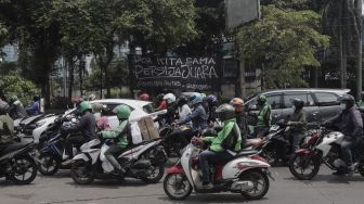 Sejumlah kendaraan melintas di depan spanduk Persija Jakarta juara Piala Menpora 2021 yang terpasang di kawasan Pasar Minggu, Jakarta, Senin (26/4/2021). [Suara.com/Angga Budhiyanto]