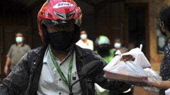 Pengendara sepeda motor menerima takjil yang dibagikan secara Drive Thru di GPIB Bukit Moria, Jalan Prof.Dr.Soepomo, Kecamatan Tebet, Jakarta Selatan, Senin (26/4/2021). [Suara.com/Dian Latifah]