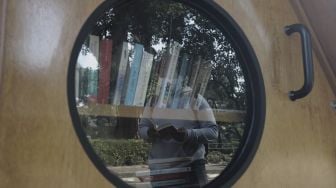 Refleksi warga membaca buku di perpustakaan bersama Bookhive Jakarta di kawasan Taman Situ Lembang, Jakarta, Selasa (27/4/2021). [Suara.com/Angga Budhiyanto]