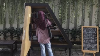 Warga memilih koleksi buku di perpustakaan bersama Bookhive Jakarta di kawasan Taman Situ Lembang, Jakarta, Selasa (27/4/2021). [Suara.com/Angga Budhiyanto]