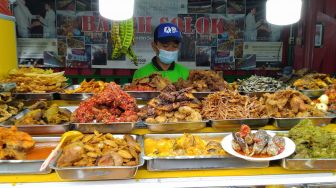 Pedagang nasi kapau menunggu pembeli di Food Street Kramat di Kawasan Senen, Jakarta Pusat, Selasa (27/4/2021). [Suara.com/Alfian Winanto]