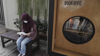 Warga membaca buku di perpustakaan bersama Bookhive Jakarta di kawasan Taman Situ Lembang, Jakarta, Selasa (27/4/2021). [Suara.com/Angga Budhiyanto]