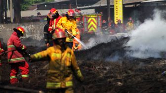 Petugas menyemprotkan air ke tumpukan ban bekas di Kawasan Desa Bojong Nangka, Gunung Putri, Bogor, Selasa (27/4/2021). [Suara.com/Dian Latifah]
