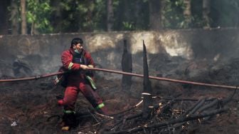 Petugas menarik selang  dii Kawasan Desa Bojong Nangka, Gunung Putri, Bogor, Selasa (27/4/2021). [Suara.com/Dian Latifah]