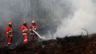 Petugas menyemprotkan air ke tumpukan ban bekas di Kawasan Desa Bojong Nangka, Gunung Putri, Bogor, Selasa (27/4/2021). [Suara.com/Dian Latifah]