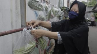 Warga memilah sayuran yang dijajakan secara gratis di Jalan Jati Padang VI RT 002 RW 004, Pasar Minggu, Jakarta Selatan, Rabu (28/4/2021). [Suara.com/Angga Budhiyanto]