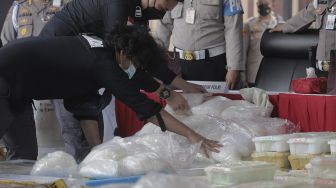 Penyidik Dirtipid Narkoba Bareskrim Polri menata barang bukti sabu sebelum gelar kasus jaringan internasional di Lapangan Bhayangkara Mabes Polri, Jakarta, Rabu (28/4/2021). [Suara.com/Angga Budhiyanto]