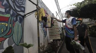 Warga memilih pakaian bekas layak pakai yang dijajakan secara gratis di Jalan Jati Padang VI RT 002 RW 004, Pasar Minggu, Jakarta Selatan, Rabu (28/4/2021). [Suara.com/Angga Budhiyanto]