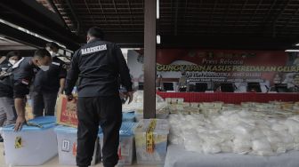 Penyidik Dirtipid Narkoba Bareskrim Polri menata barang bukti sabu sebelum gelar kasus jaringan internasional di Lapangan Bhayangkara Mabes Polri, Jakarta, Rabu (28/4/2021). [Suara.com/Angga Budhiyanto]