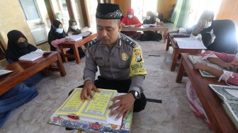 Polisi Aipda Syaiful Annam memberi contoh cara membaca Al Quran kepada anak-anak di Masjid An-Nuur, Kelurahan Tamanan, Kota Kediri, Jawa Timur, Kamis (29/4/2021). ANTARA FOTO/Prasetia Fauzani
