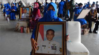 Keluarga korban tenggelamnya KRI Nanggala 402 memegang foto prajurit KRI Nanggala-402 yang gugur saat Penganugerahan tanda kehormatan dan kenaikan pangkat luar biasa prajurit KRI Nanggala-402 di Pusat Penerbangan TNI Angkatan Laut, SIdoarjo, Jawa Timur, Kamis (29/4/2021).  ANTARA FOTO/Zabur Karuru