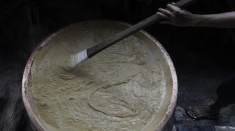 Pekerja mengaduk adonan dodol Betawi di Pondok Dodol Sari Rasa Ibu Yuyun di kawasan Pasar Minggu, Jakarta Selatan, Jumat (30/4/2021). [Suara.com/Angga Budhiyanto]