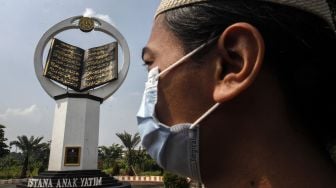 Warga melintas di depan tugu Al Quran di Masjid Istana Anak Yatim, Desa Cikeas Udik, Gunung Putri, Kabupaten Bogor, Jawa Barat, Jumat (30/4/2021).  ANTARA FOTO/Yulius Satria Wijaya
