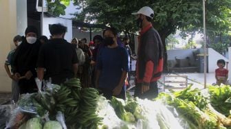 Warga mengantre untuk mengambil sayuran saat kegiatan bazar sayuran gratis di Masjid Ar Ruhama, Jati Padang, Jakarta, Minggu (2/5/2021). [Suara.com/Dian Latifah]