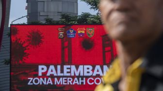 Warga melintas di Jalan Jenderal Sudriman dengan latar videotron bertuliskan Palembang zona merah COVID-19 di Palembang, Sumatera Selatan, Senin (3/5/2021). ANTARA FOTO/Nova Wahyudi