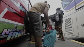 Sejumlah calon penumpang memasukkan barang bawaanya ke dalam bagasi bus di Terminal Pulo Gebang, Jakarta Timur, Selasa (4/5/2021). [Suara.com/Angga Budhiyanto]