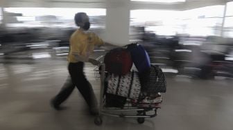 Porter membawakan barang bawaan calon penumpang di Terminal Pulo Gebang, Jakarta Timur, Selasa (4/5/2021). [Suara.com/Angga Budhiyanto]