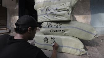 Pekerja menuliskan alamat pada barang yang akan dikirim via jasa ekspedisi kereta api di Jalan Bungur Raya, Senen, Jakarta, Selasa (4/5/2021). [Suara.com/Angga Budhiyanto]