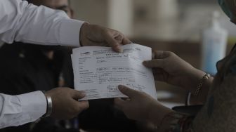 Amil zakat memberikan tanda terima zakat kepada Umat Islam usai membayar zakat fitrah di Masjid Istiqlal, Jakarta, Rabu (5/5/2021). [Suara.com/Angga Budhiyanto]