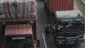 Pengemudi berjalan memasuki truknya saat terjebak kemacetan di jalan Tol Jakarta-Cikampek, Cikarang, Kabupaten Bekasi, Jawa Barat, Kamis (6/5/2021). [Suara.com/Angga Budhiyanto]