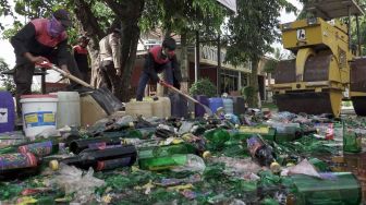 Petugas memusnahkan barang bukti miras pabrikan di Polresta Banyumas, Jateng, Jumat (7/5/2021). ANTARA FOTO/Idhad Zakaria
