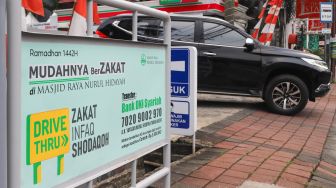 Papan informasi pemberitahuan zakat secara drive thru terpasang di Masjid Nurul Hidayah, Tanah Kusir, Jakarta Selatan, Sabtu (8/5/2021). [Suara.com/Alfian Winanto]