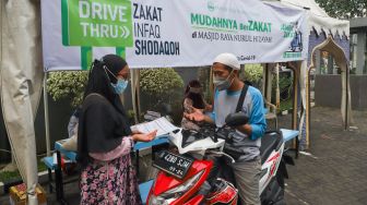 Warga membayar zakat secara drive thru di Masjid Nurul Hidayah, Tanah Kusir, Jakarta Selatan, Sabtu (8/5/2021). [Suara.com/Alfian Winanto]