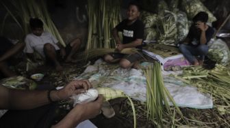 Pedagang menyelesaikan pembuatan kulit ketupat di Pasar Palmerah, Jakarta, Minggu (9/5/2021). [Suara.com/Angga Budhiyanto]