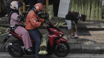 Warga bergegas pergi usai membeli janur di Pasar Palmerah, Jakarta, Minggu (9/5/2021). [Suara.com/Angga Budhiyanto]