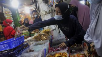 Pembeli memilih kue kering di Pasar Mester Jatinegara, Jakarta, Minggu (9/5/2021). [Suara.com/Dian Latifah]