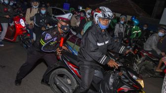 Petugas kepolisian menertibkan pemudik motor yang berhenti di pinggir ruas jalan setelah diputar balik di jalur pantura Karawang, Jawa Barat, Senin (10/5/2021). [ANTARA FOTO/M Ibnu Chazar]