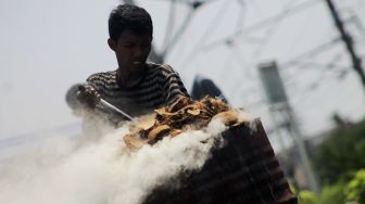 Pekerja membakar batok kelapa di dalam drum di Kawasan Gang Sentiong, Kramat, Jakarta Pusat, Senin (10/5/2021). [Suara.com/Dian Latifah]