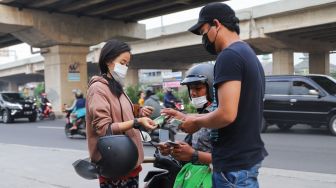 Warga menukar uang ke penjual jasa penukaran uang di Kalimalang, Jakarta Timur, Rabu (Penjual menunjukkan uang baru yang siap untuk ditukar di Kalimalang, Jakarta Timur, Rabu (12/5/2021). [Suara.com/Alfian Winanto].