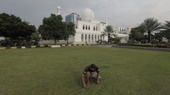 Petugas merapikan jarak untuk salat Idul Fitri 1442 Hijriah di lapangan Masjid Agung Al-Azhar, Jakarta Selatan, Rabu (12/5/2021). [Suara.com/Angga Budhiyanto]