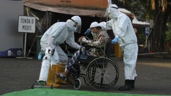 Tenaga kesehatan membantu seorang pasien COVID-19 usai pelaksanaan shalat Idul Fitri di halaman Rumah Sakit Lapangan Indrapura (RSLI) di Surabaya, Jawa Timur, Kamis (13/5/2021). [ANTARA FOTO/Moch Asim]