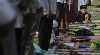 Seorang anak beristirahat saat sejumlah umat Muslim menunaikan ibadah Salat Idul Fitri 1442 H di lingkungan Masjid Al-Azhar, Jakarta, Kamis (13/5/2021). [Suara.com/Angga Budhiyanto]