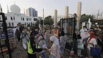 Petugas memeriksa suhu tubuh umat Muslim yang akan menunaikan ibadah Salat Idul Fitri 1442 H di lingkungan Masjid Al-Azhar, Jakarta, Kamis (13/5/2021). [Suara.com/Angga Budhiyanto]