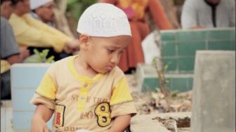 Viral Foto Pilu Anak Duduk di Samping Makam Bawa Buku Yasin, Ini Kisahnya