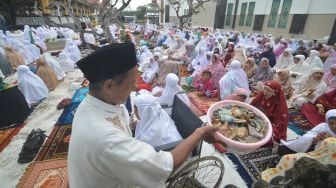 Seorang jamaah mengumpulkan infak sebelum pelaksanaan shalat Idul Fitri Tarekat Syattariyah di kawasan kompleks Makam Syekh Burhanuddin, Ulakan, Kabupaten Padangpariaman, Sumatera Barat, Jumat (14/5/2021). FOTO/Iggoy el Fitra
