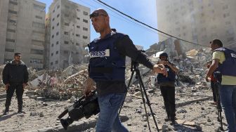 Jurnalis Palestina meliput Menara Jala yang hancur setelah serangan udara Israel di Jalur Gaza, Palestina, pada (15/5/2021). [MOHAMMED ABED / AFP]