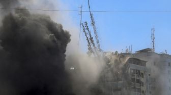 Asap mengepul dari Menara Jala saat runtuh setelah dibom dalam serangan udara Israel di Kota Gaza, Palestina, pada (15/5/2021). [MOHAMMED ABED / AFP]
