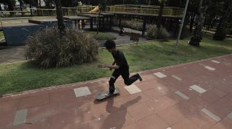 Seorang anak bermain papan seluncur (skateboard) di Taman Puring, Kebayoran Baru, Jakarta, Minggu (16/5/2021). [Suara.com/Angga Budhiyanto]